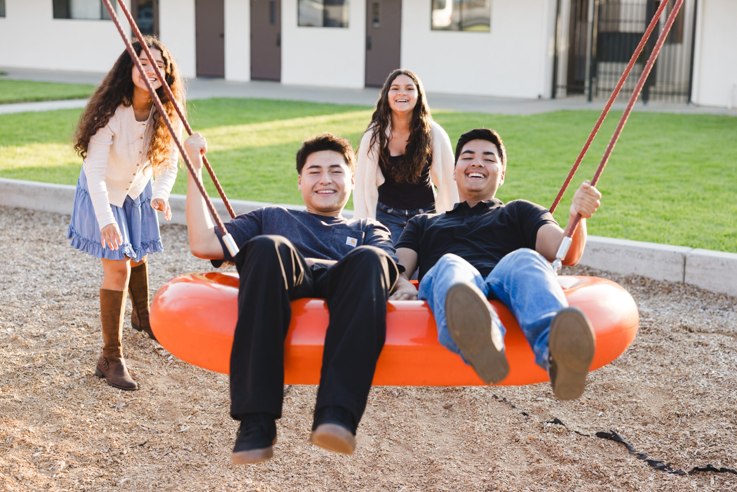 Two students laughing on the big swing outside the Live Up room