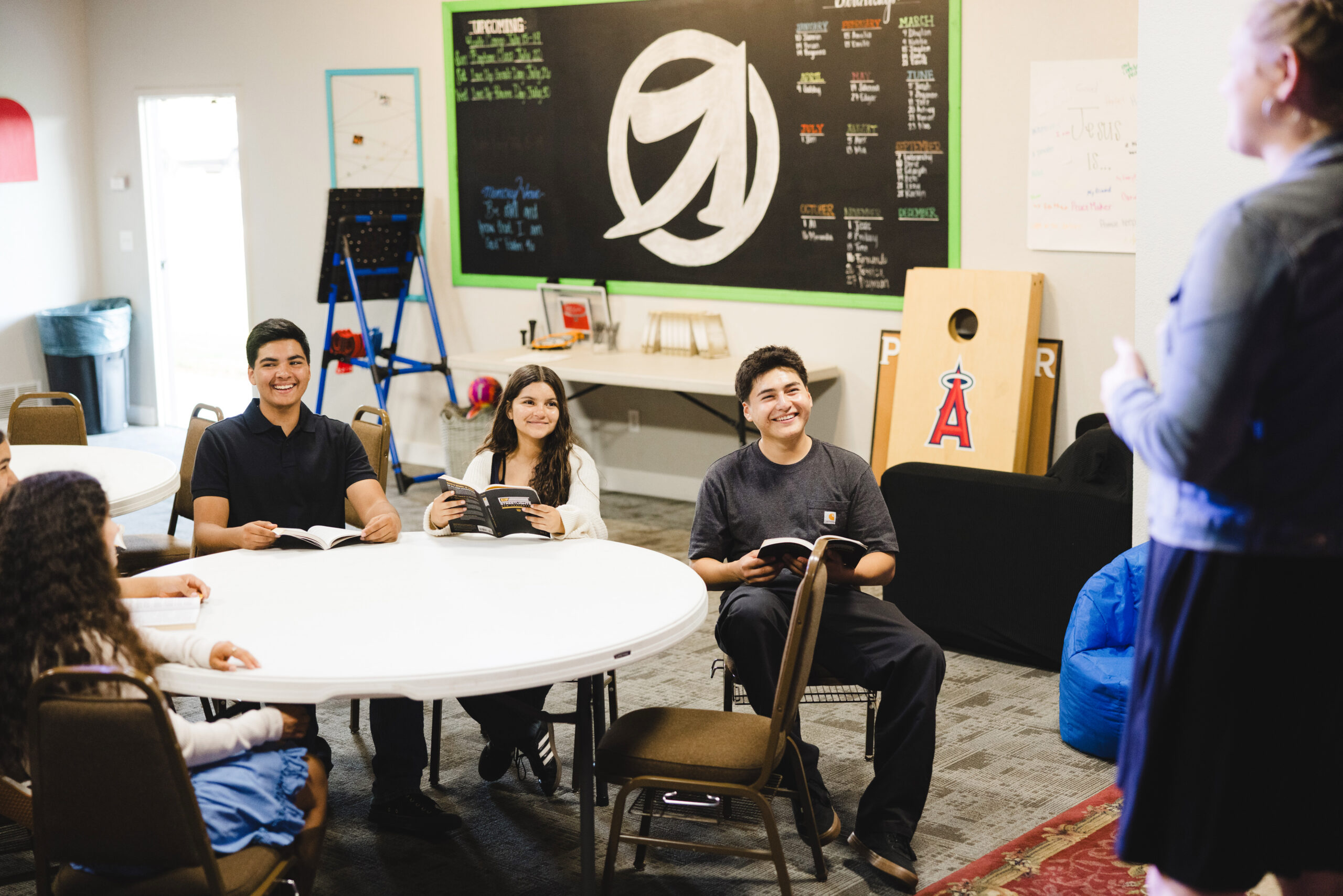 Students with Bibles talking around tables in the Live Up room