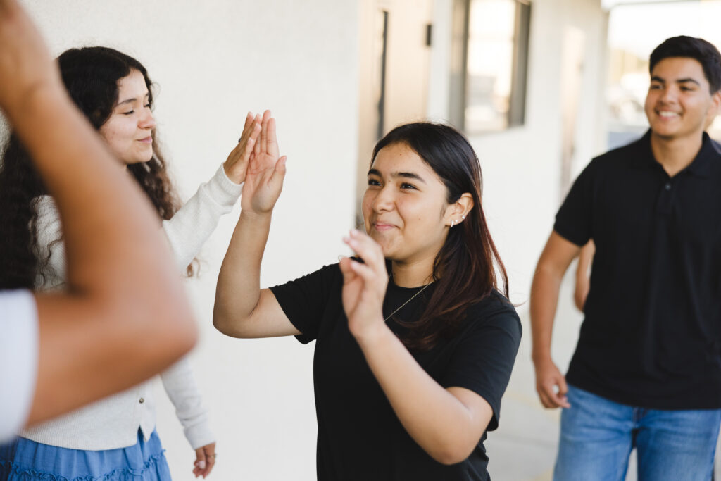 Young adults high-fiving and laughing at a Vida Church event in Santa Maria